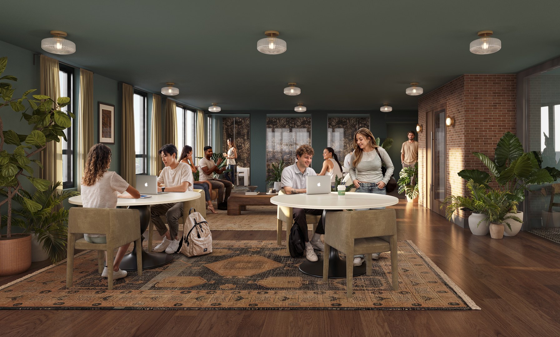 Modern lounge with large windows, round tables, and plants; several young adults sit and work on laptops or talk, while others stand or walk in the background. Ideal for Purdue off campus housing, the room has green walls and a warm, inviting atmosphere.