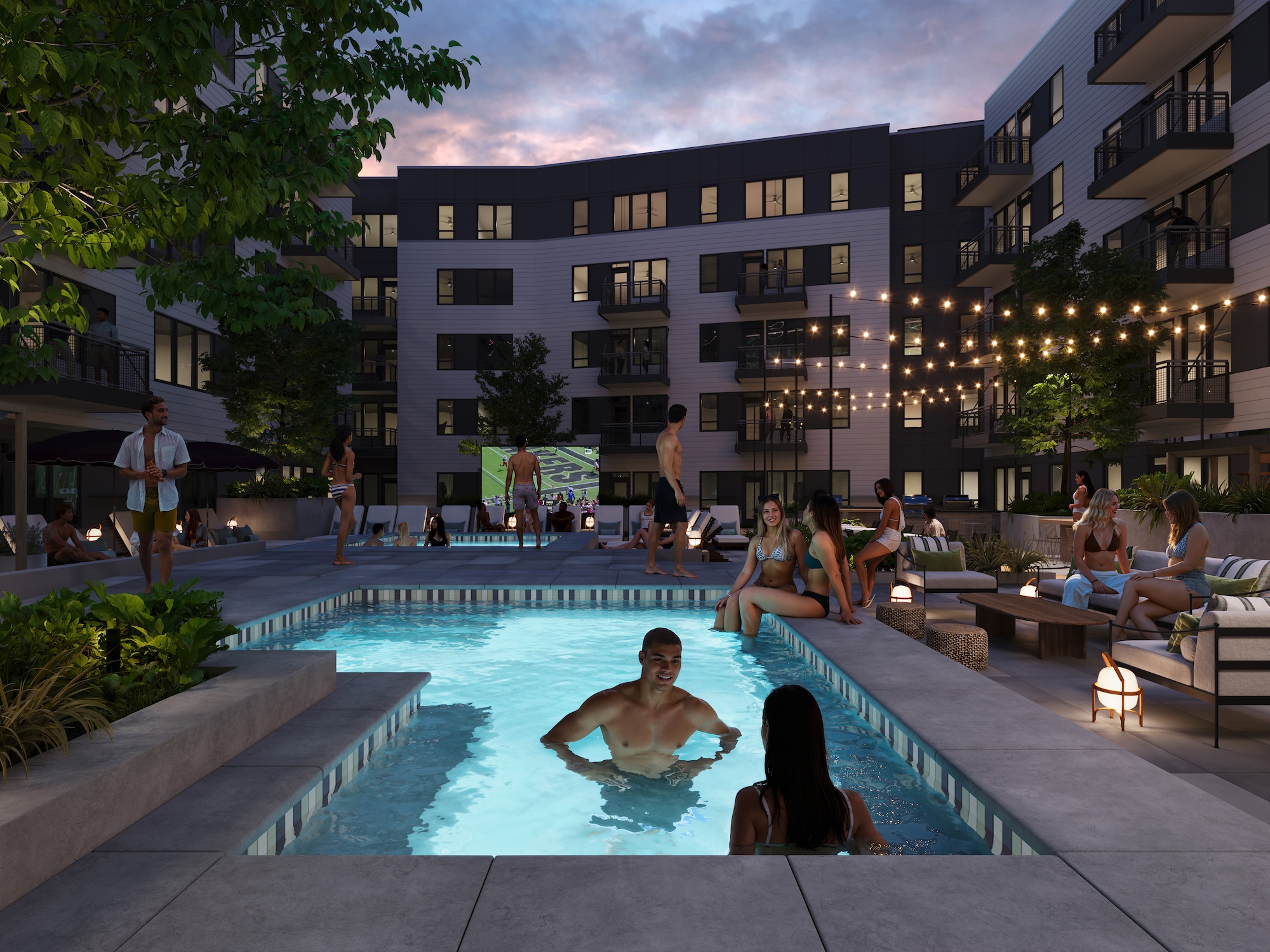 People relax and socialize around a lit outdoor pool at a Purdue off campus housing community in the evening, with string lights, seating areas, and an outdoor screen in the background.