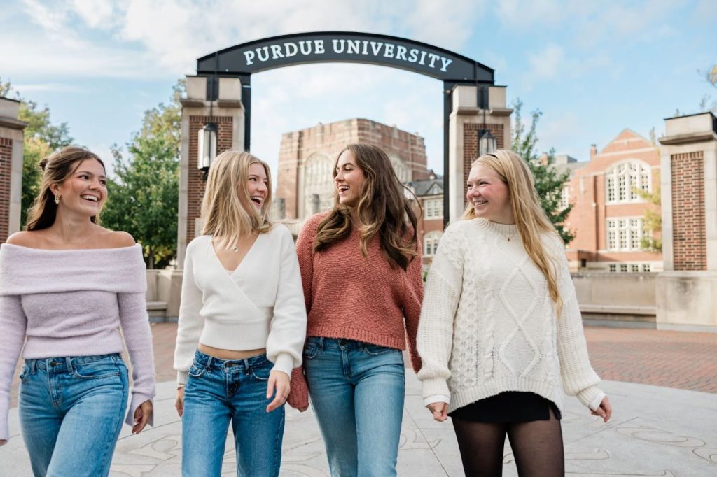 Four Purdue University students walking and laughing together on campus in West Lafayette.