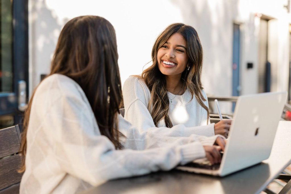 Two Purdue students at a coffee shop working on their laptops.
