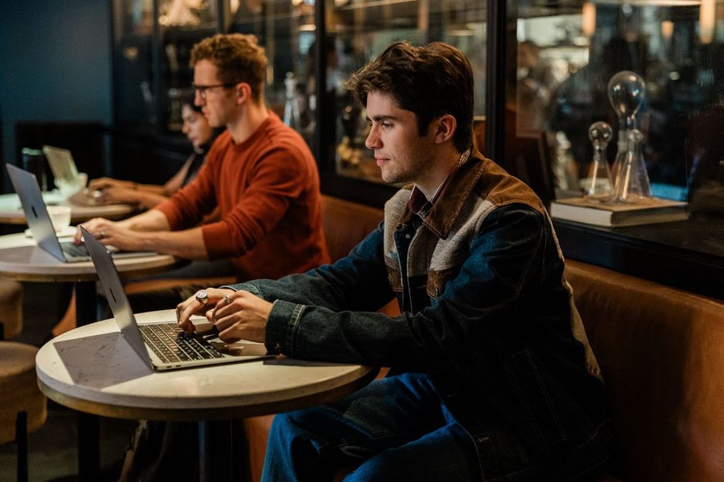 A Purdue student sitting at a coffee shop, focused on his laptop while working.