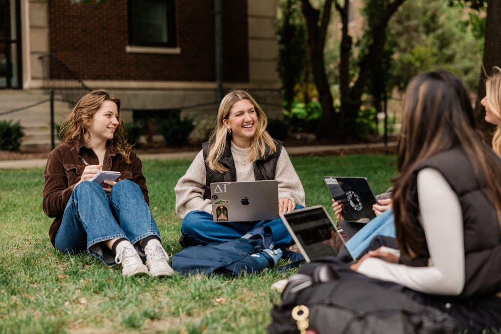 A group of Purdue students sit outside on-campus with laptops and notebooks in West Lafayette.