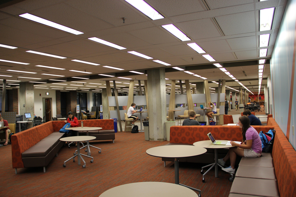 Interior view of Hicks Undergraduate Library with students studying at desks and tables. 